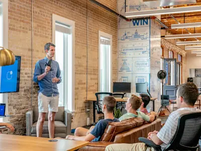man giving a presentation to a group of other men in a bright industrial office